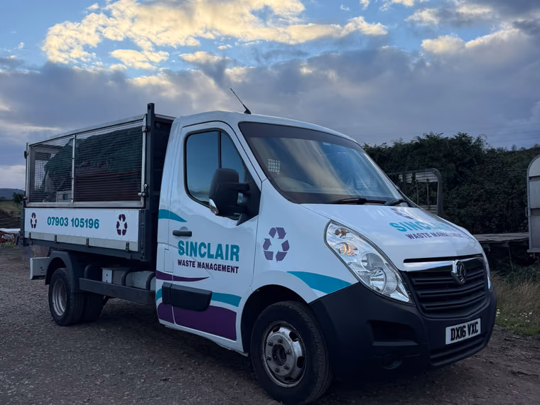 The Sinclair Waste Management cage tipper van in white, teal and purple livery, parked on gravel