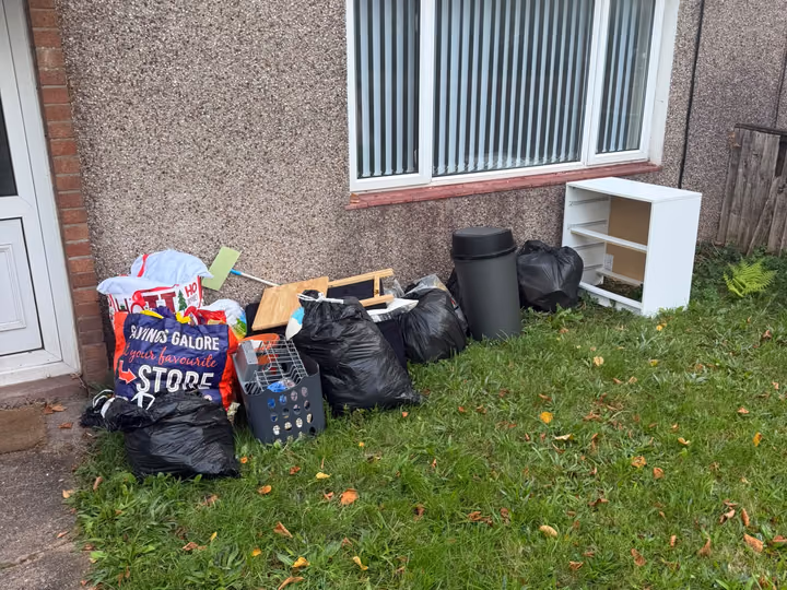 Before: bagged rubbish and furniture removed from a lawn