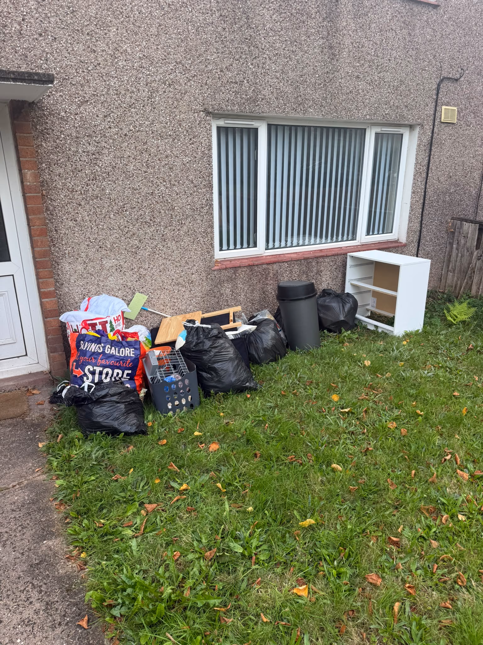 Before: bagged rubbish and furniture removed from a lawn
